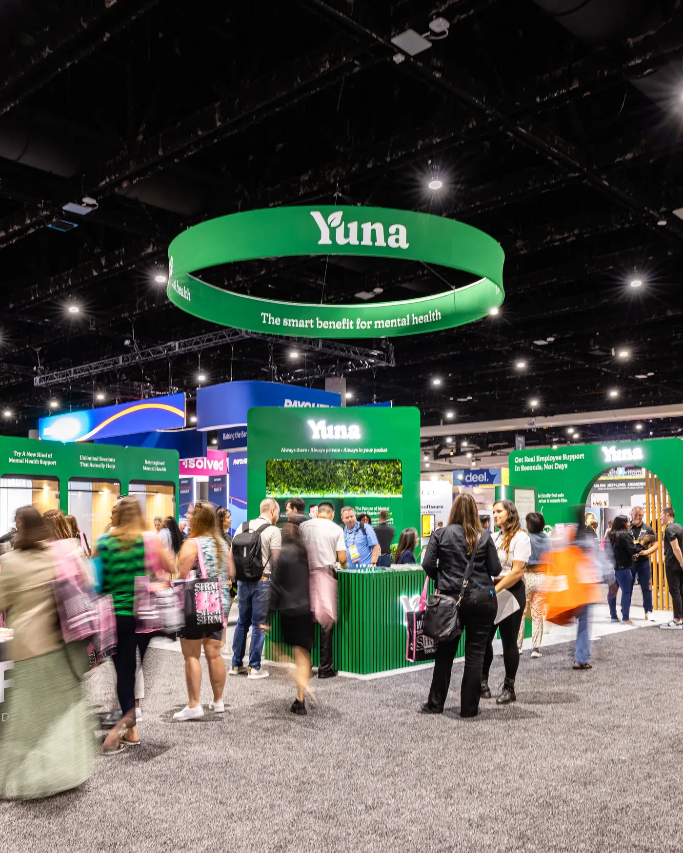 Crowds visiting Yuna's booth beneath its circular banner at the SHRM conference