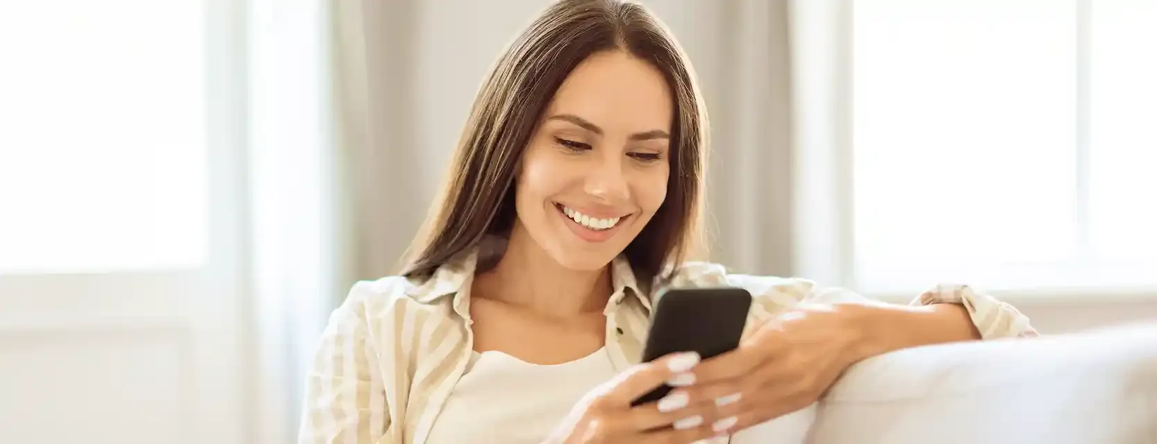 A person relaxing at home, smiling while using Yuna on their phone.