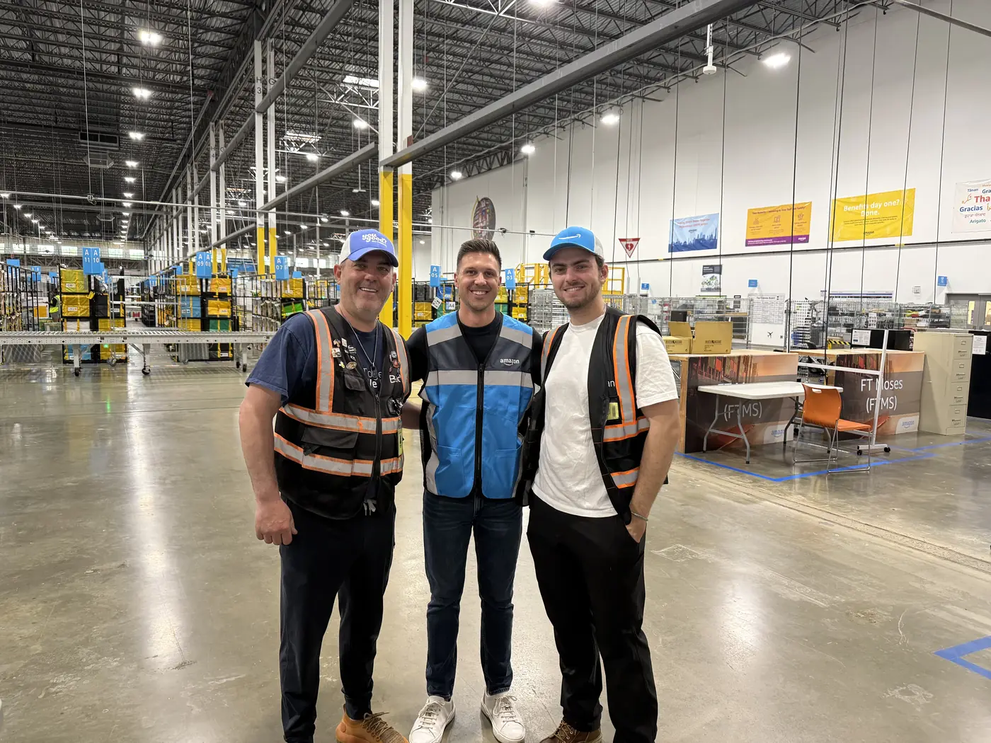 Two DSP leaders in safety vests standing with Yuna CEO Grant Winns inside an Amazon delivery station